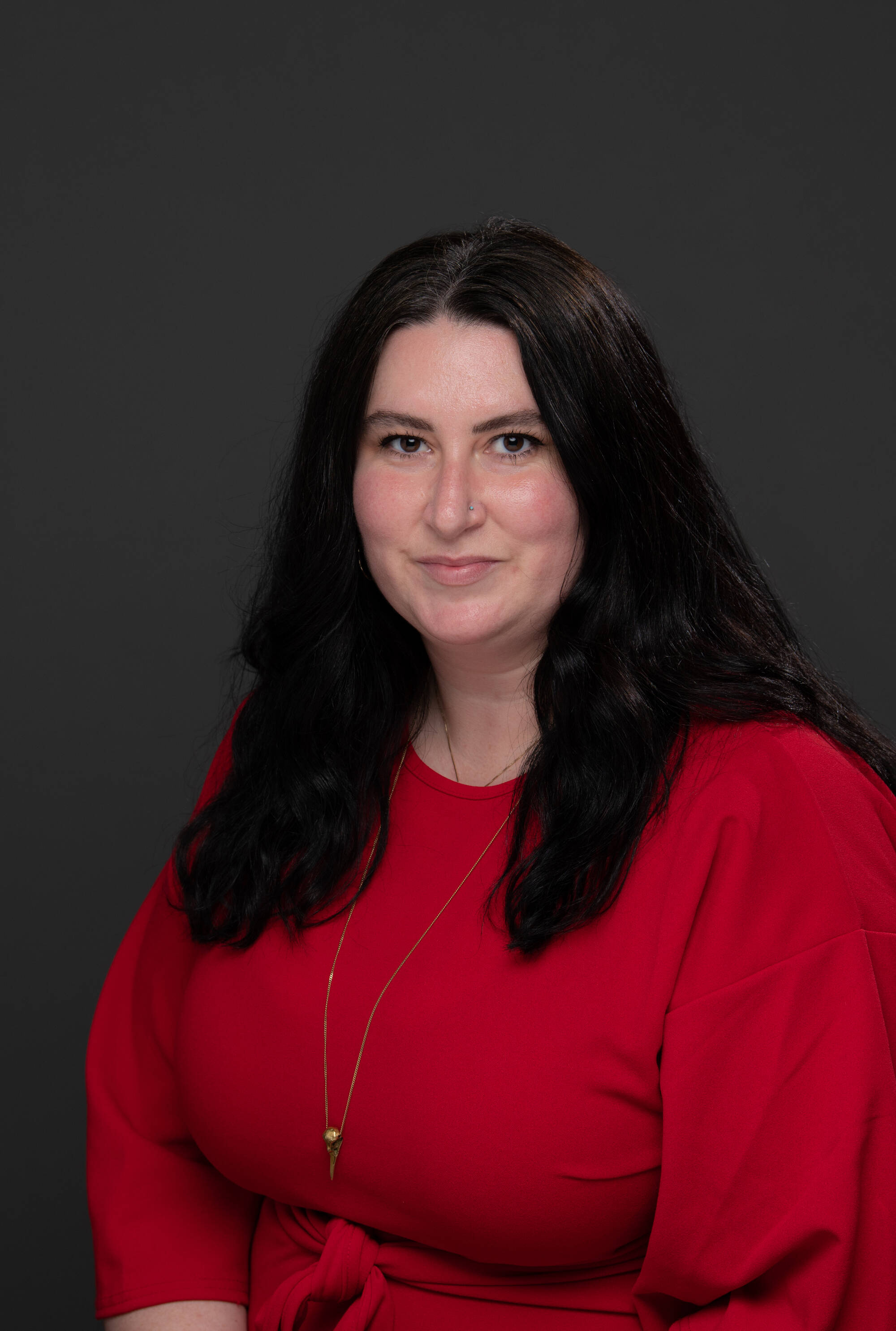 Allison Bazaire in a red blouse on a dark background.